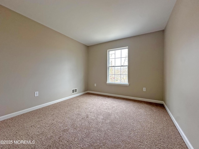 spare room featuring carpet flooring, visible vents, and baseboards