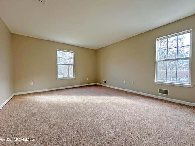 carpeted empty room with visible vents and baseboards