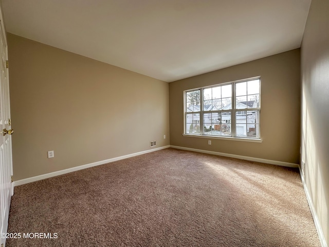 spare room featuring carpet, visible vents, and baseboards