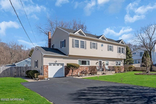 view of front facade with fence, a chimney, a front lawn, a garage, and brick siding