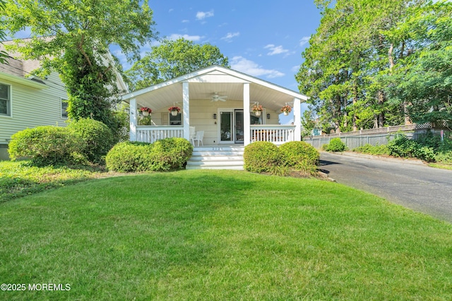 view of front of house with a ceiling fan, a front yard, covered porch, and fence