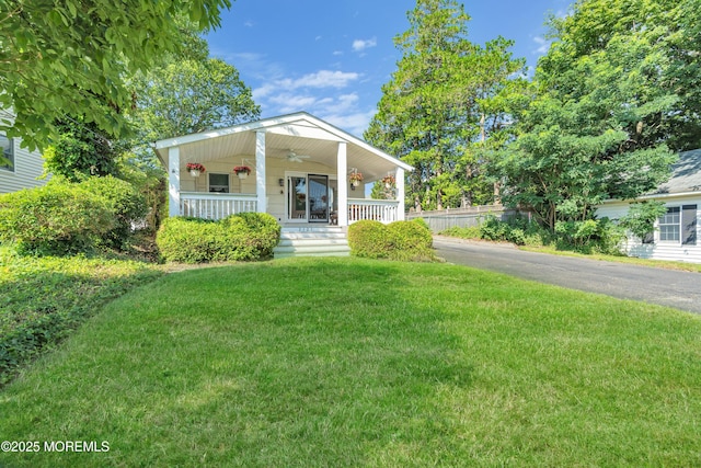 view of front of house with covered porch, a ceiling fan, and a front yard