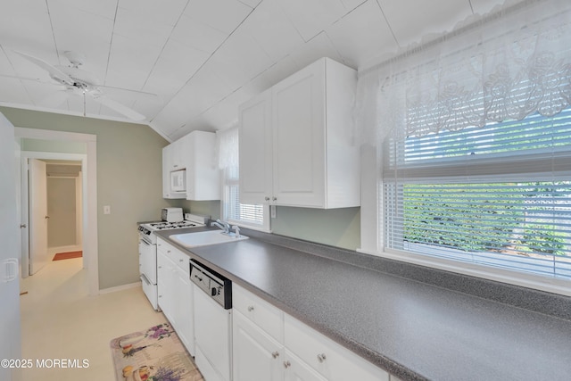 kitchen with white appliances, a sink, baseboards, vaulted ceiling, and white cabinets