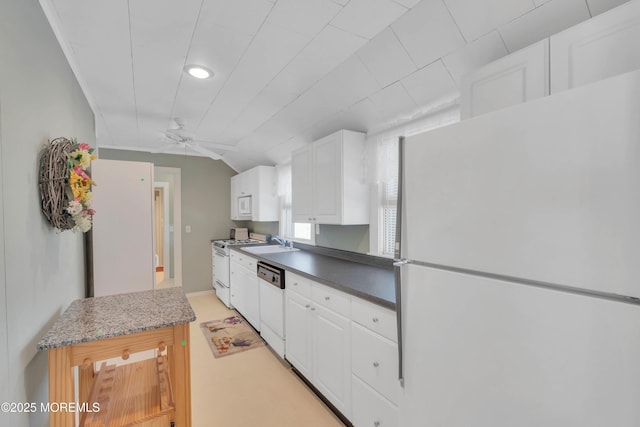 kitchen featuring lofted ceiling, white appliances, a sink, and white cabinetry