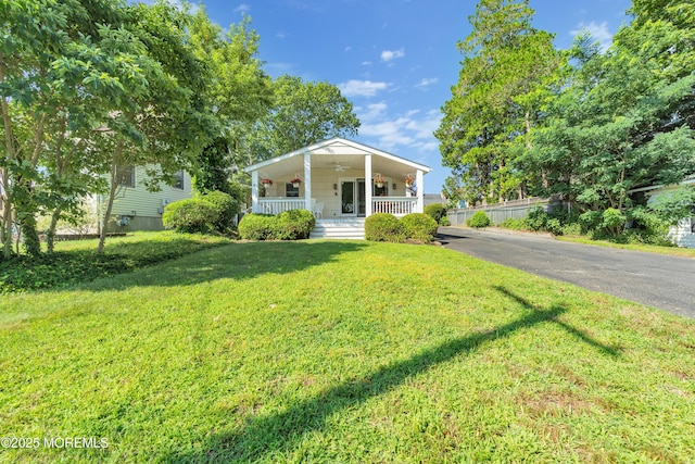 bungalow featuring covered porch, ceiling fan, a front yard, and driveway