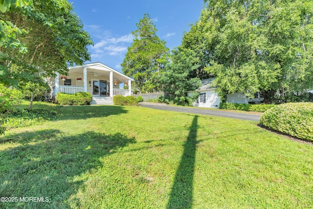 view of yard with ceiling fan and a porch