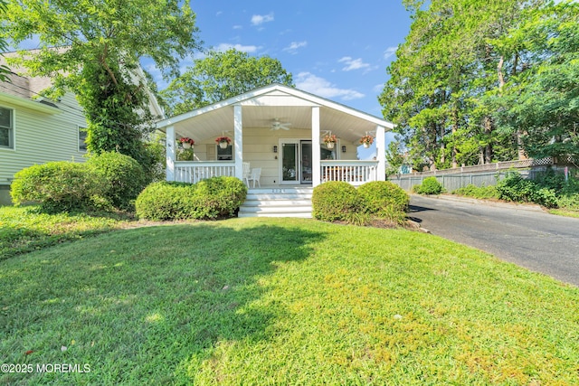 view of front of home with ceiling fan, fence, a porch, and a front yard