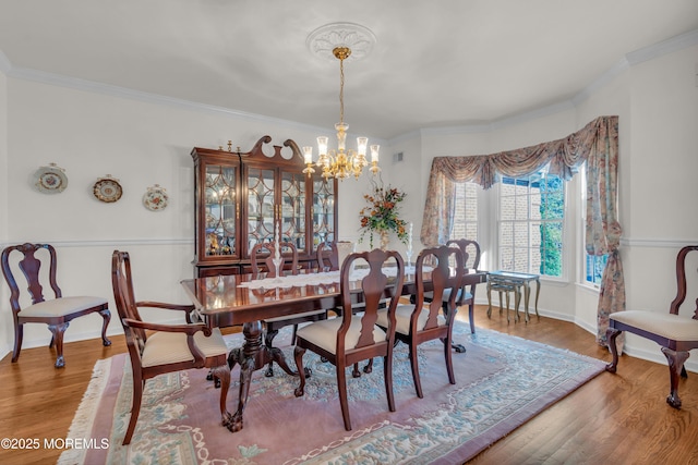 dining area with baseboards, an inviting chandelier, wood finished floors, and crown molding