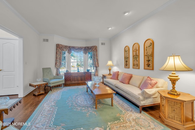 living area with visible vents, ornamental molding, baseboards, and wood finished floors