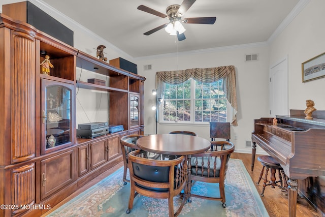 dining space with visible vents, wood finished floors, and ornamental molding