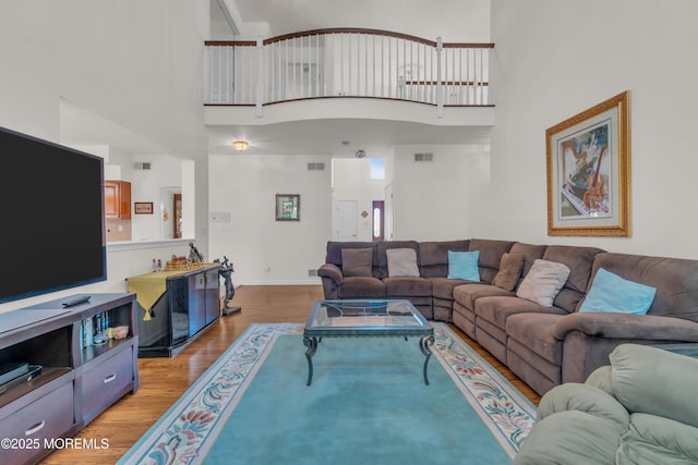 living area featuring visible vents, a towering ceiling, and light wood finished floors