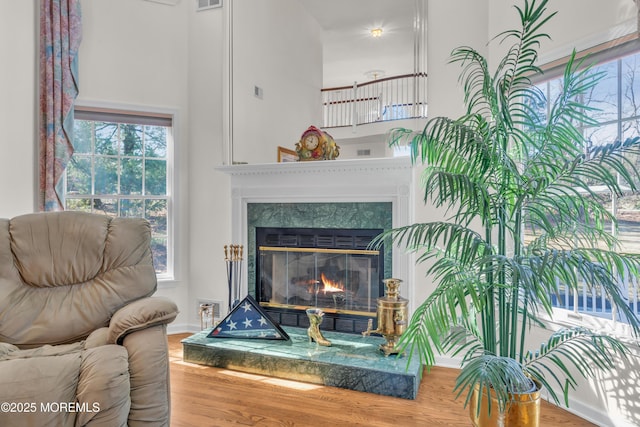 interior details featuring visible vents, wood finished floors, baseboards, and a glass covered fireplace