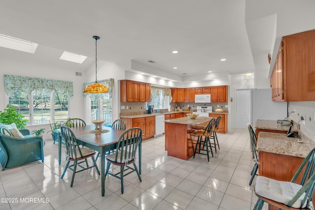 dining room featuring a skylight, plenty of natural light, and light tile patterned floors