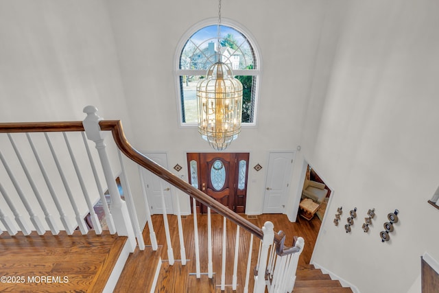 interior space with a high ceiling, wood finished floors, a wealth of natural light, and a chandelier