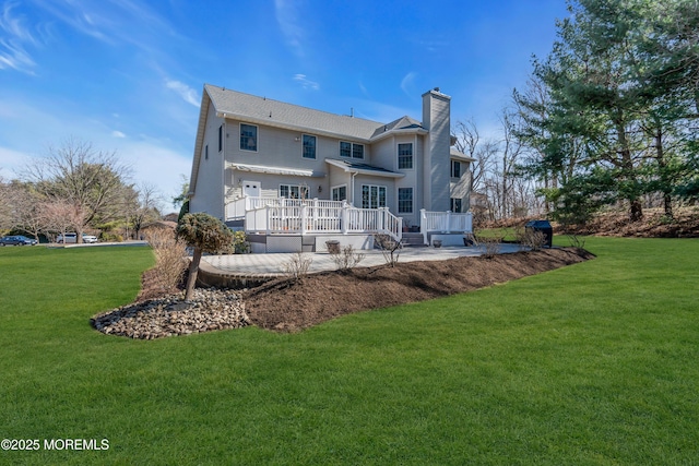 rear view of house with a lawn, a deck, and a chimney