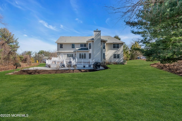 back of property with a wooden deck, a yard, and a chimney