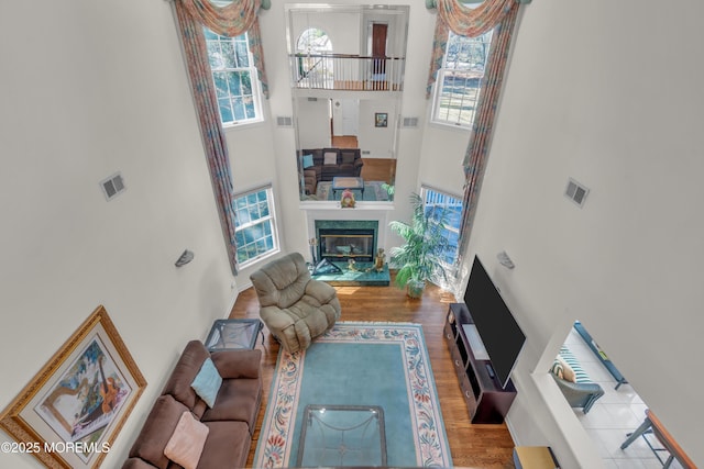 living area featuring visible vents, a high ceiling, wood finished floors, and a fireplace