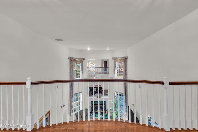 hallway featuring an upstairs landing, visible vents, and wood finished floors