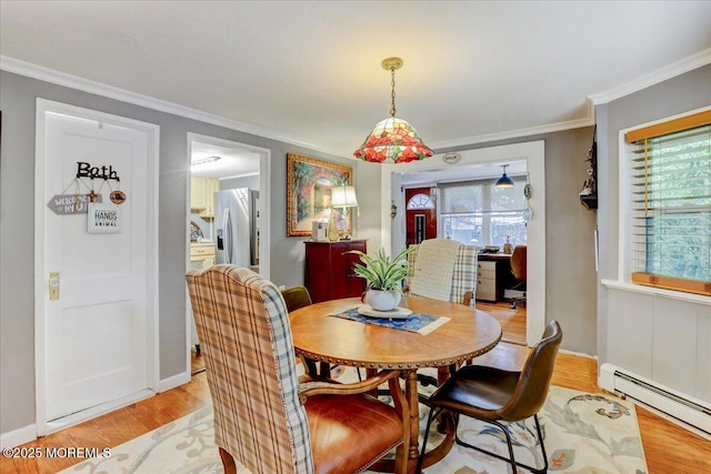 dining room with light wood finished floors, plenty of natural light, baseboard heating, and crown molding