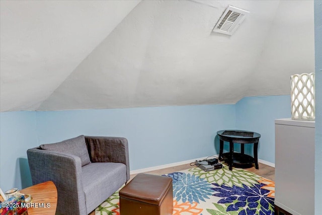 sitting room with lofted ceiling, baseboards, visible vents, and wood finished floors