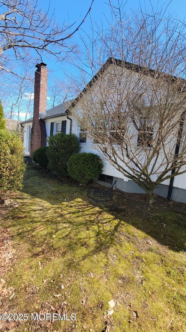 view of side of home with a yard and a chimney