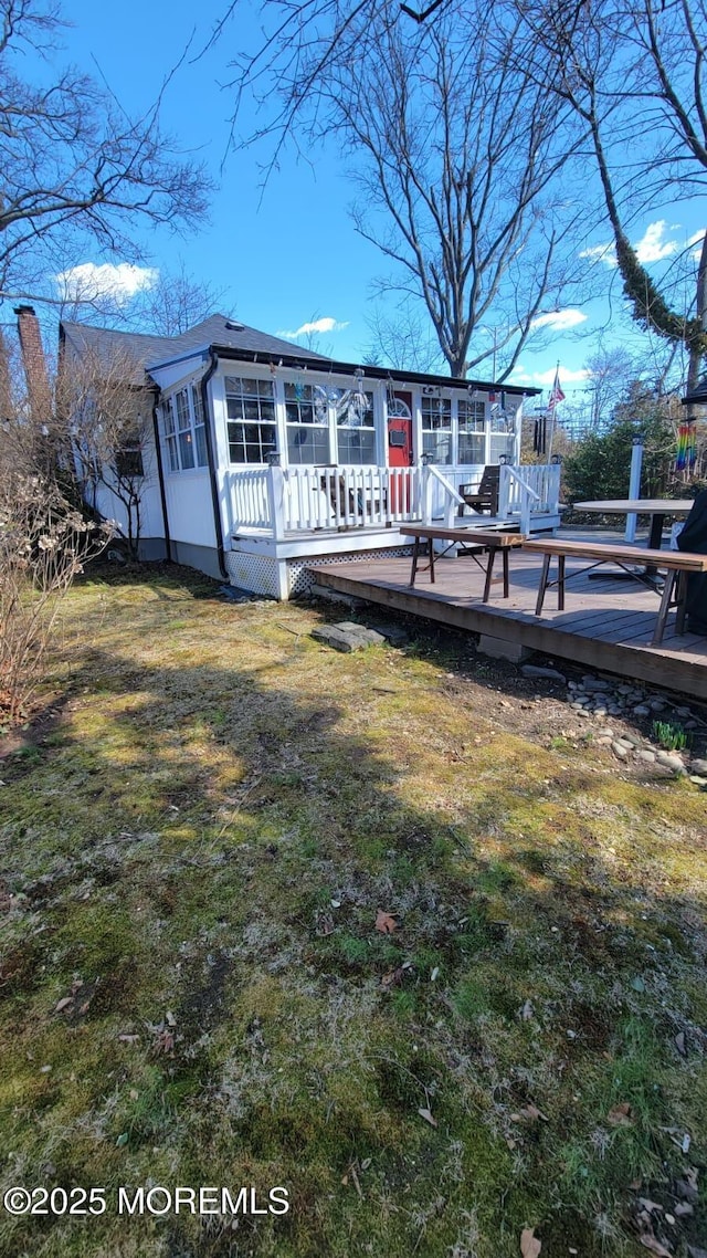 exterior space featuring a front yard, a sunroom, and a wooden deck