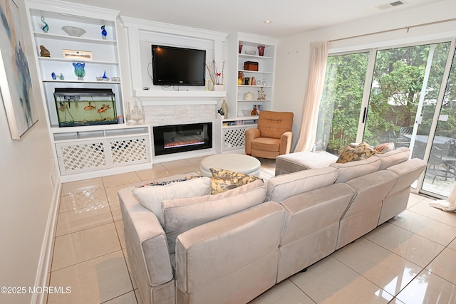 living area featuring tile patterned flooring, visible vents, built in features, and a glass covered fireplace