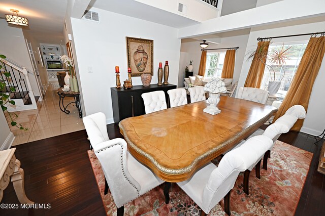 dining room featuring stairway, baseboards, visible vents, and dark wood-type flooring