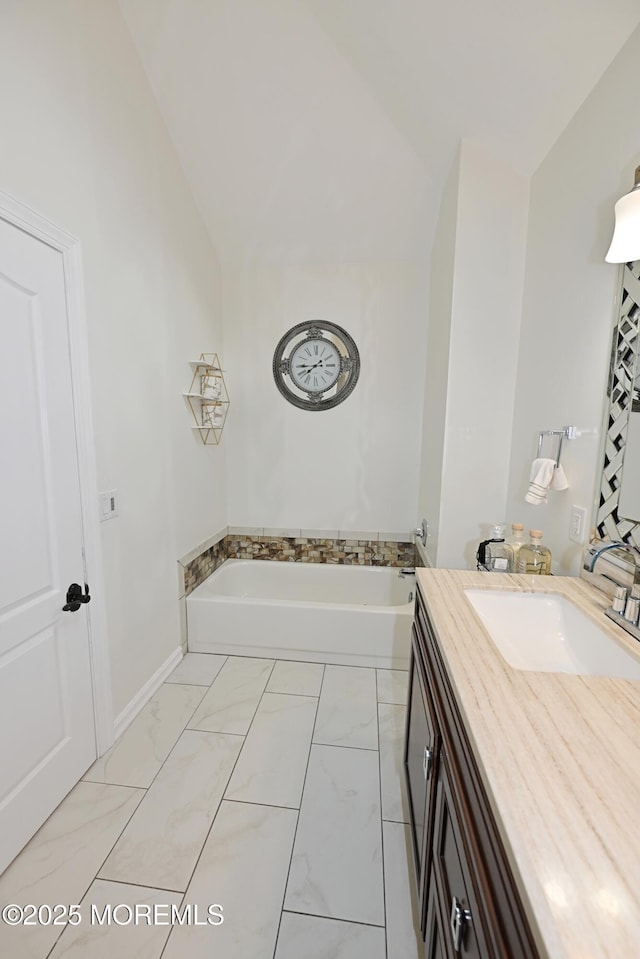 full bathroom with lofted ceiling, marble finish floor, a bathtub, and vanity