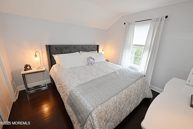 bedroom with vaulted ceiling, dark wood-style floors, and baseboards