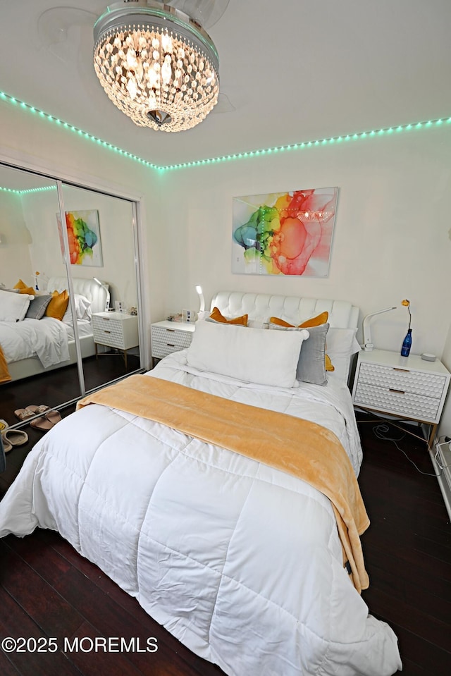 bedroom with a closet, a chandelier, and wood finished floors