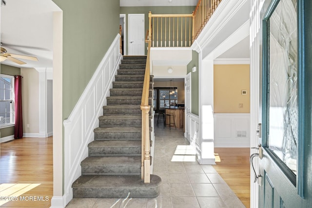 entrance foyer featuring a decorative wall, wood finished floors, visible vents, a ceiling fan, and stairs