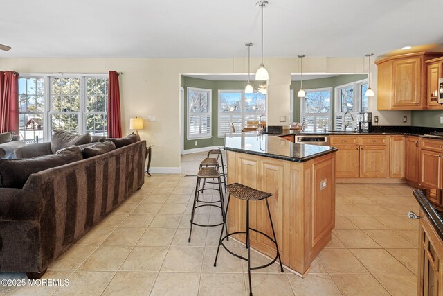 kitchen featuring decorative light fixtures, a breakfast bar area, light tile patterned floors, open floor plan, and baseboards