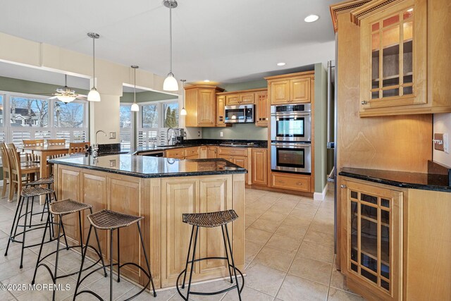 kitchen featuring glass insert cabinets, appliances with stainless steel finishes, a kitchen breakfast bar, a sink, and recessed lighting