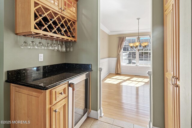 bar featuring a dry bar, a wainscoted wall, wine cooler, crown molding, and light tile patterned flooring