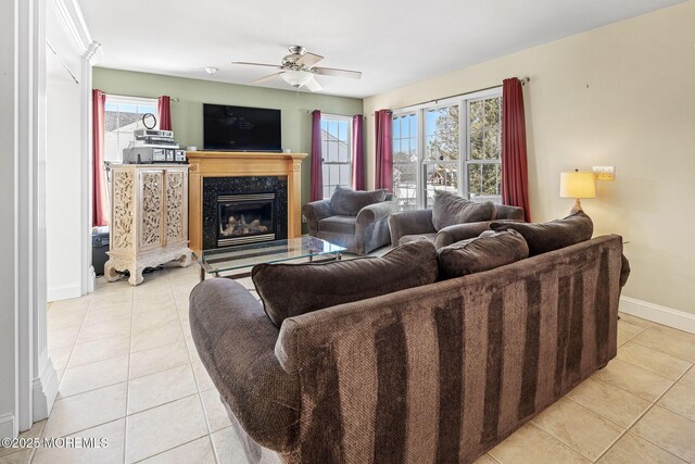 living area with light tile patterned flooring, ceiling fan, baseboards, and a premium fireplace