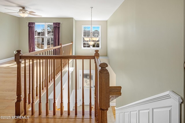 stairs with baseboards, a wealth of natural light, and ceiling fan with notable chandelier