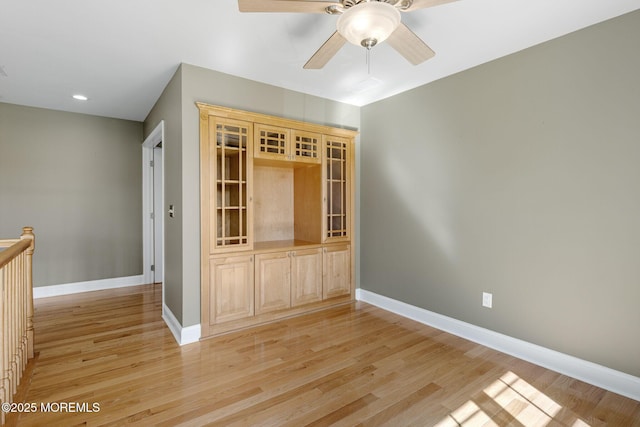 unfurnished room featuring a ceiling fan, light wood-style flooring, and baseboards