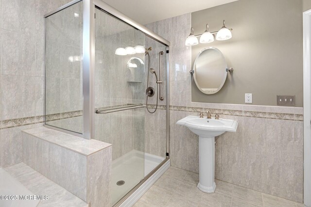 full bath featuring a stall shower, a wainscoted wall, tile walls, and tile patterned floors