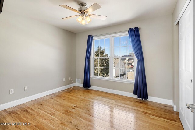 empty room featuring light wood-style floors, visible vents, ceiling fan, and baseboards