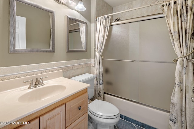 full bath with toilet, wainscoting, shower / bath combo with shower curtain, and vanity