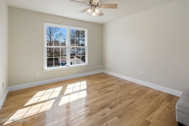 spare room with light wood-style floors, visible vents, baseboards, and a ceiling fan