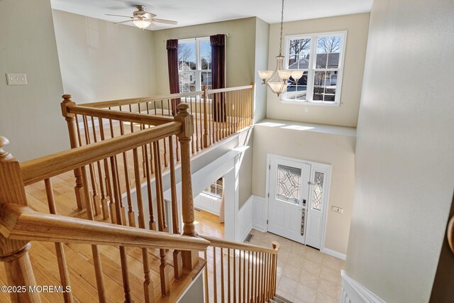 stairs with visible vents, baseboards, and ceiling fan with notable chandelier