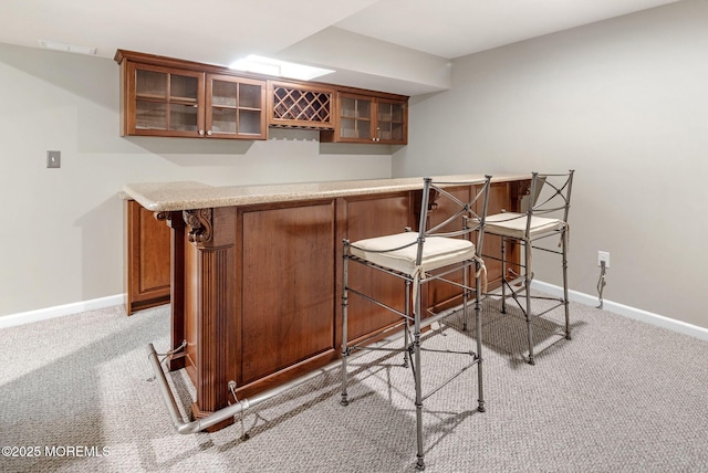 bar with baseboards, light colored carpet, and a bar