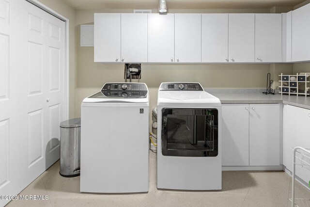 laundry room featuring cabinet space, light tile patterned floors, and separate washer and dryer