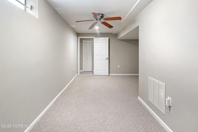 carpeted empty room featuring a ceiling fan, visible vents, and baseboards