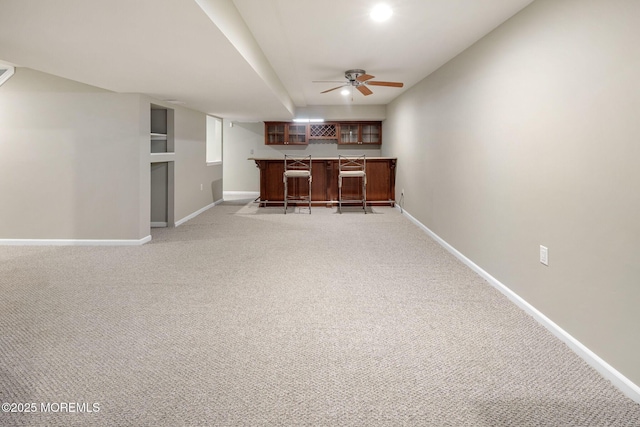 unfurnished living room with a ceiling fan, light colored carpet, indoor bar, and baseboards