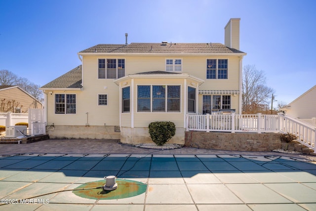 back of property featuring a chimney, fence, a fenced in pool, and a patio