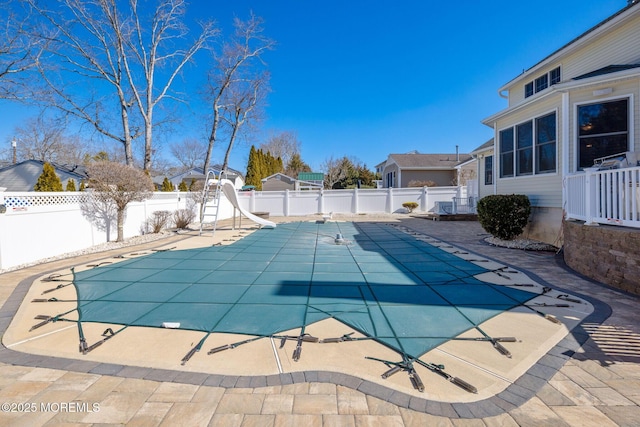 view of swimming pool with a patio area, a fenced backyard, a fenced in pool, and a water slide