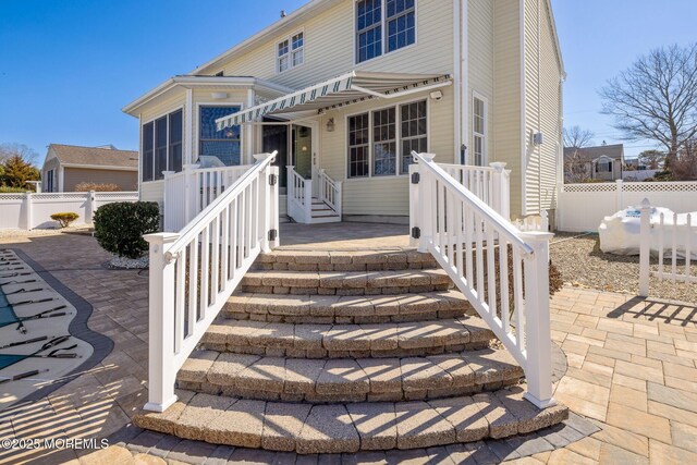 view of front facade featuring a sunroom, a patio area, and fence